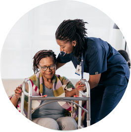 Senior with walker being assisted by health care worker.